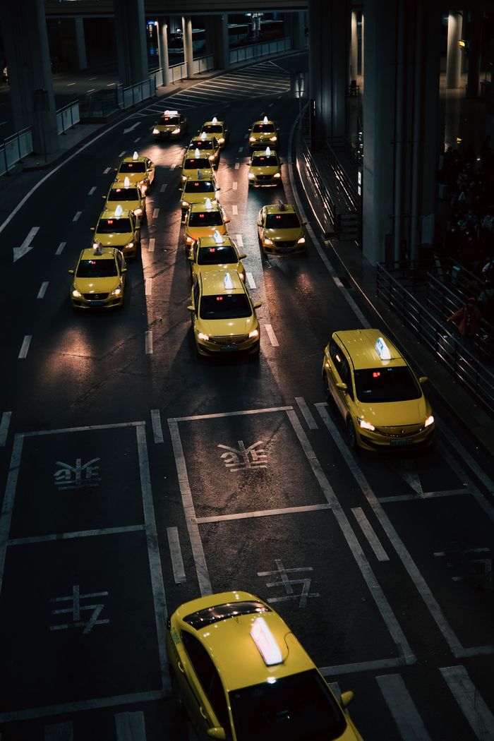 Services High angle view of lined yellow taxis on urban street during nighttime.