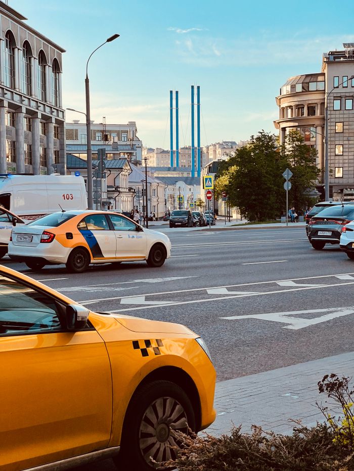 About Urban street view in Moscow featuring moving and parked vehicles, including taxis.